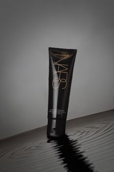 Elegant black cosmetic tube displayed on a rippling water surface, exuding luxury.