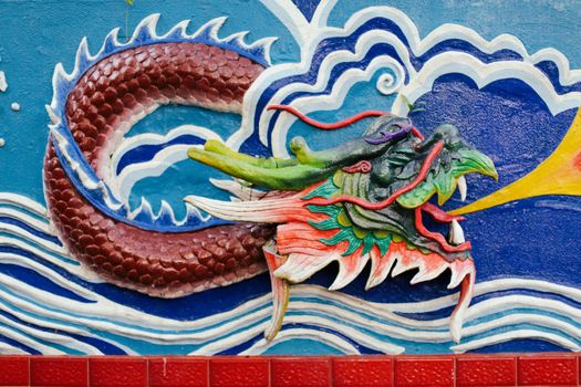 Colorful 3D dragon mural on a wall with ocean wave motifs showcasing detailed artistry.