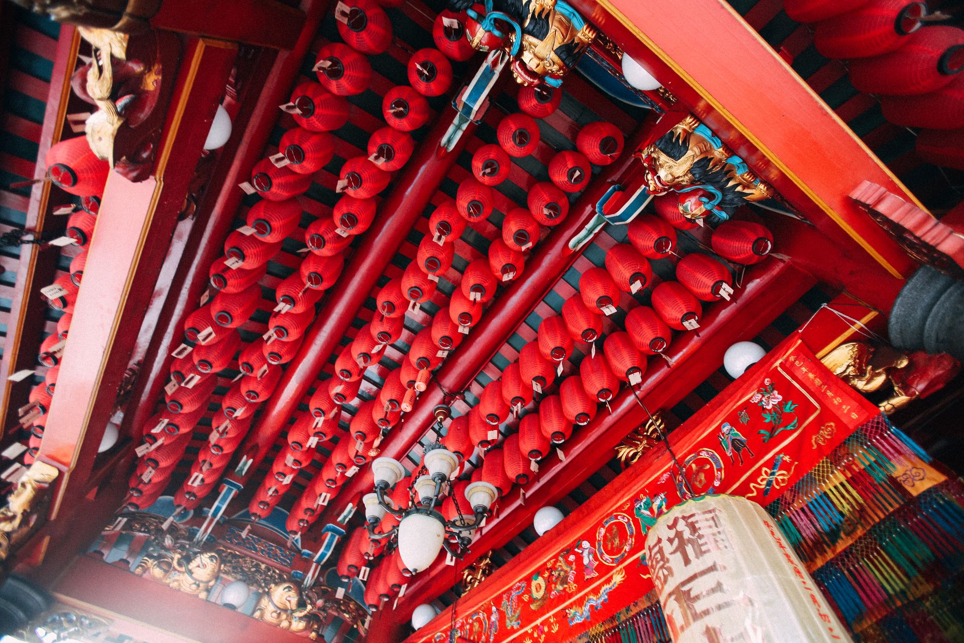 Ceiling adorned with traditional red lanterns in a Chinese temple, highlighting rich cultural decorations.