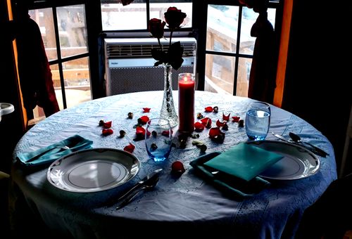 Free A beautifully set table with a candle and rose petals, creating an intimate ambiance. Stock Photo