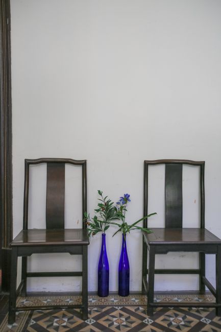 Stylish interior featuring two wooden chairs and decorative blue vases with flowers against a white wall.