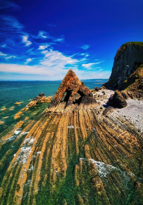 Aerial Photography of Rock Formation near Ocean under the Blue Sky