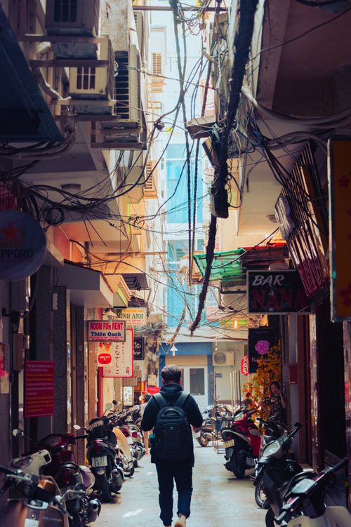 Free A busy urban alleyway with scooters and a person walking, featuring rental signs and vibrant street decor. Stock Photo