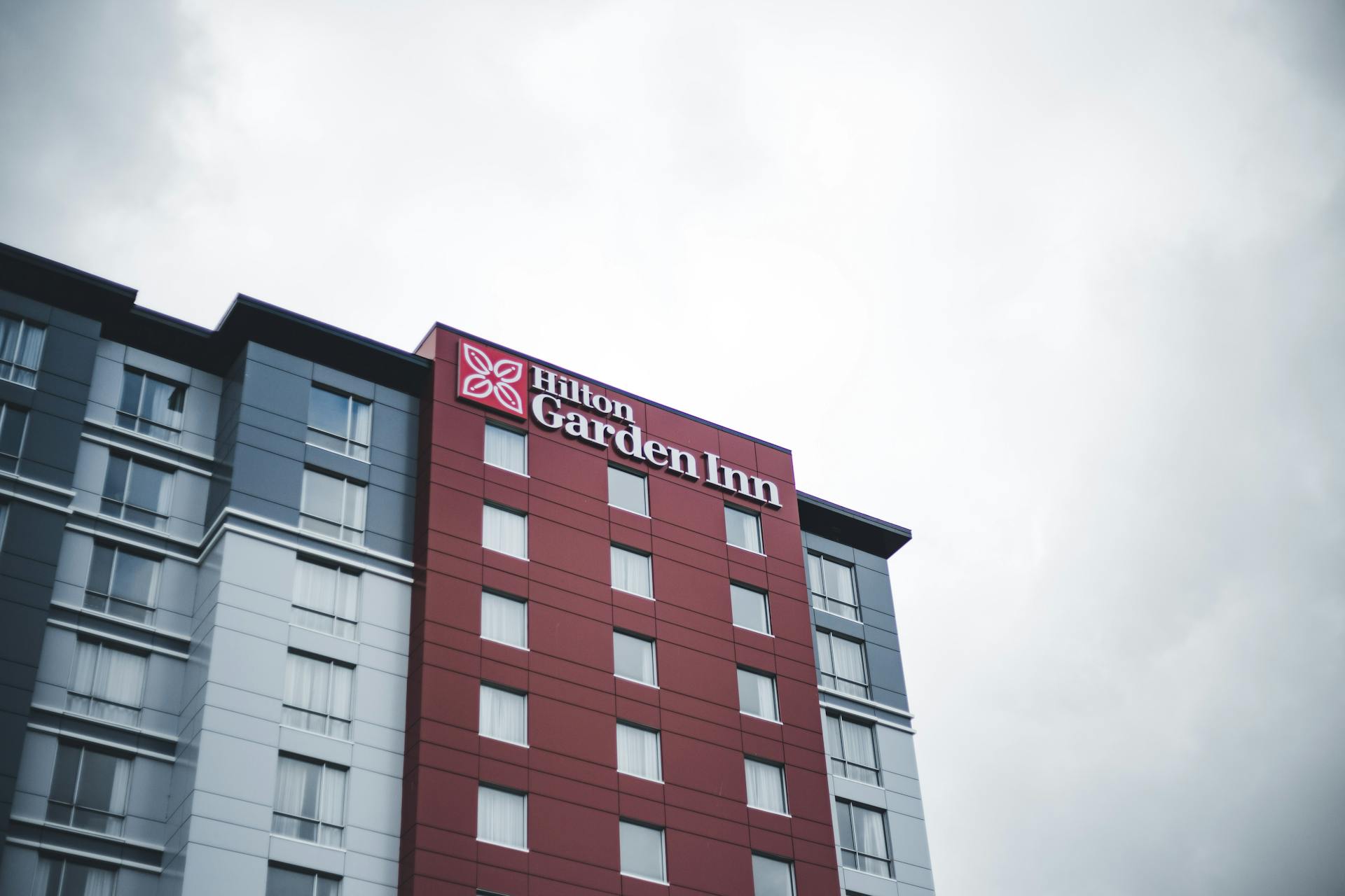 Low angle shot of Hilton Garden Inn hotel facade against a gray sky, showcasing urban architecture.