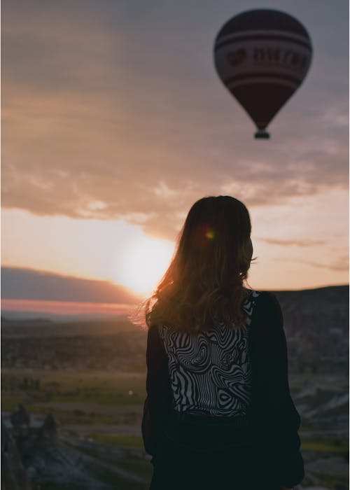 Back View of a Woman Looking the Flying Hot Air Balloon