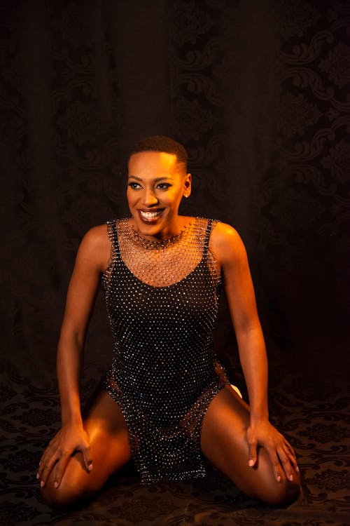 Person Wearing Makeup and a Glittery Bodysuit Posing and Smiling 