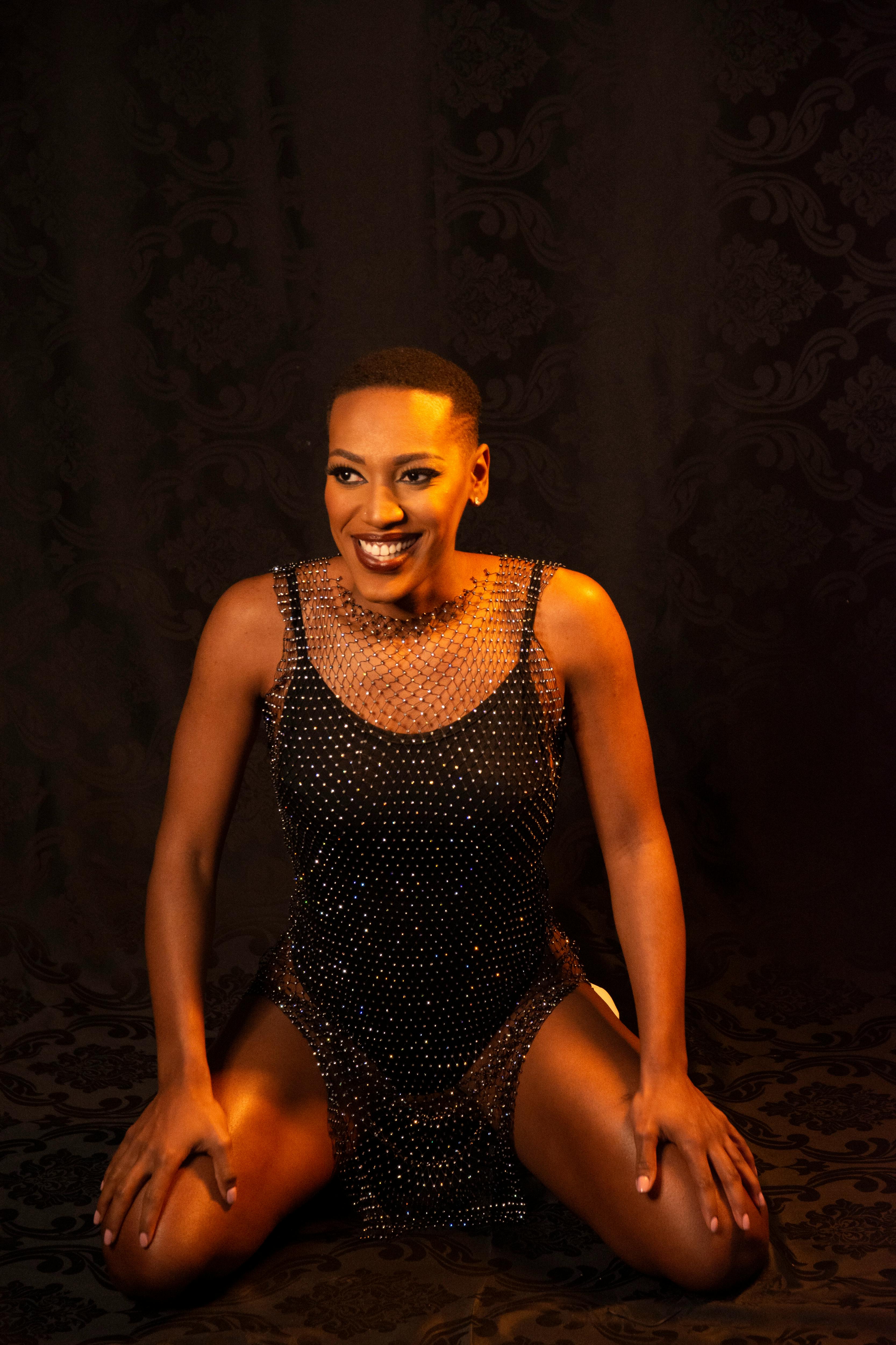 Person Wearing Makeup and a Glittery Bodysuit Posing and Smiling
