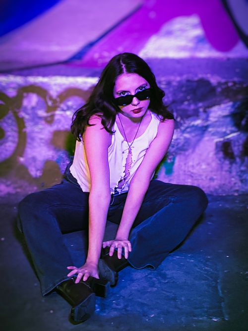 Free Stylish woman posing in a grunge urban setting with dramatic purple lighting. Stock Photo
