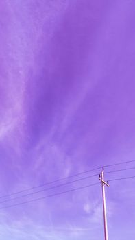 Vibrant purple sky with wispy clouds and a utility pole captured in a vertical shot.