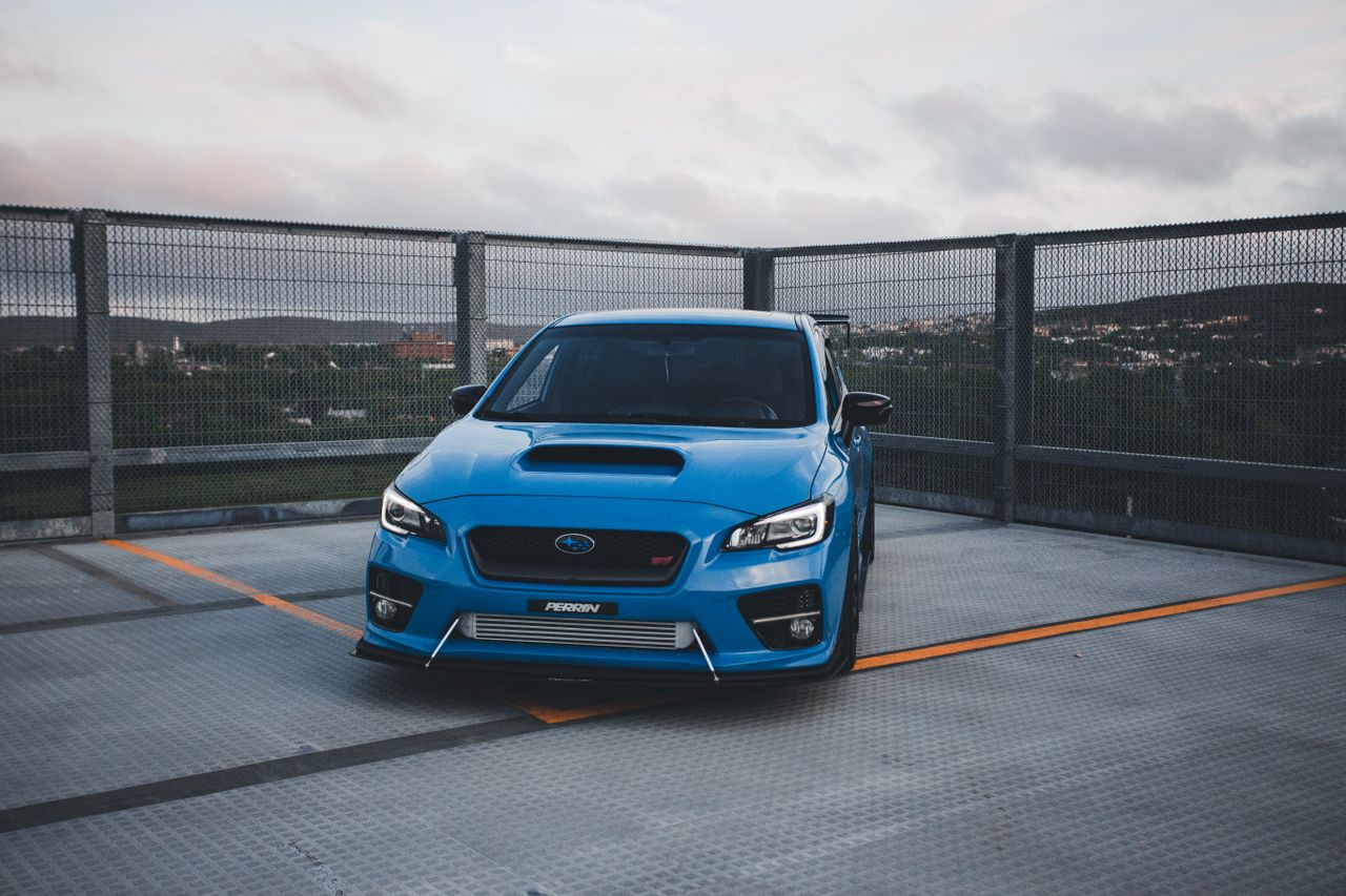 a blue luxury sports car parked on a rooftop with urban views