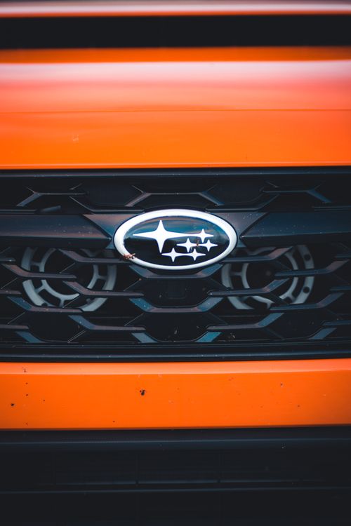 Free Detailed close-up photo showcasing the Subaru emblem on an orange vehicle grille. Stock Photo