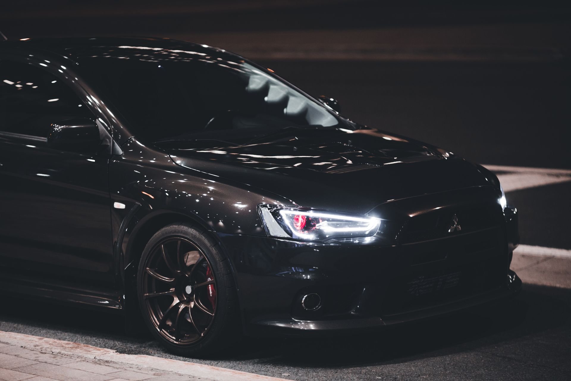 A black Mitsubishi Lancer Evolution X sports car parked at night, showcasing its modern design.