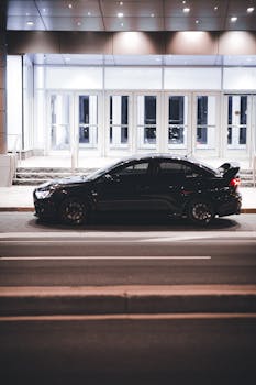 Side view of a black Mitsubishi Lancer parked on an urban street at night