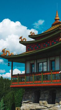 Red and green pagoda with dragon sculptures under a clear blue sky.