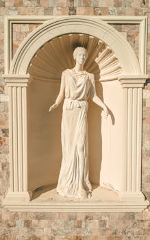 Elegant statue of a Roman woman in a classic niche, sunlight casting shadows.
