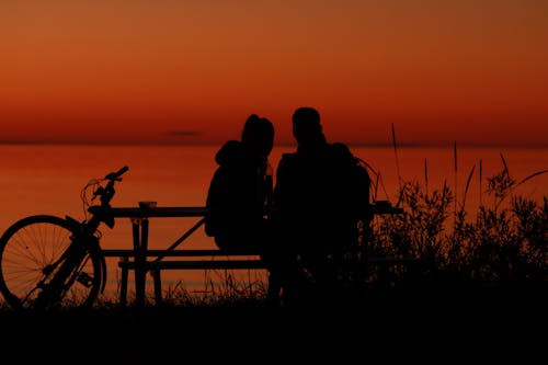 A Silhouette of a Couple Sitting Together at a Picnic Table