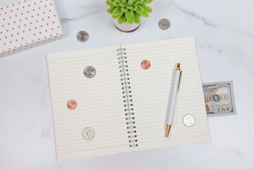 An organized workspace with a notebook, pen, and currency on a marble desk, ideal for finance planning.