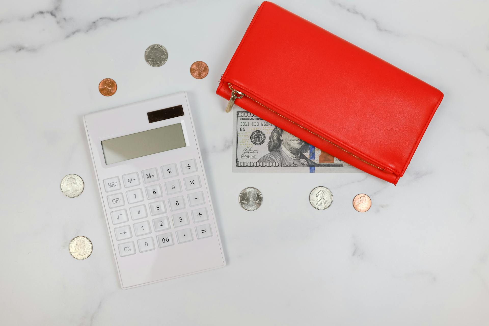 Red wallet, coins, calculator on marble. Perfect for finance or business concepts.