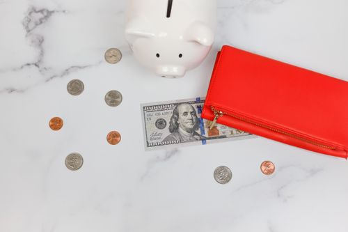 Free Overhead view of piggy bank, red wallet, and US dollars on marble surface. Stock Photo