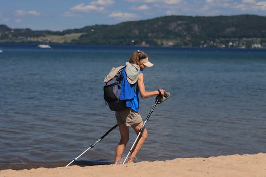 A woman hiking along a sandy beach in Jonkoping, Sweden with walking poles and a backpack.