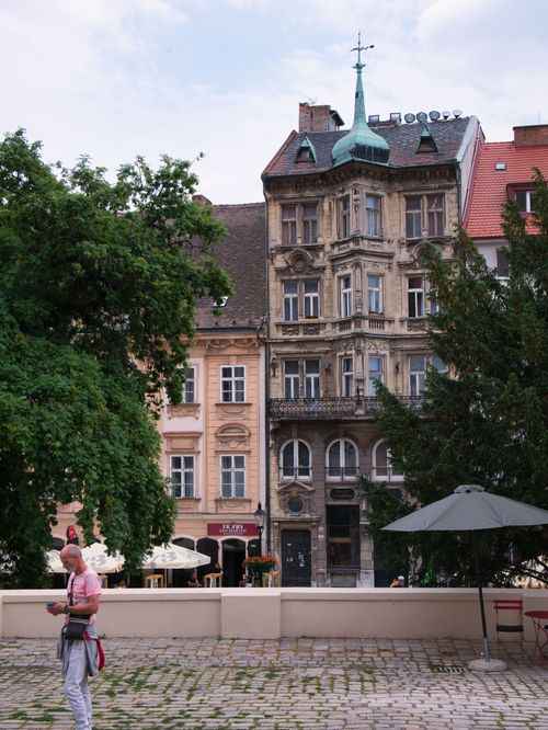 Free Picturesque view of historic European buildings with cobblestone street and trees. Stock Photo