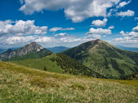 A breathtaking view of lush green mountains under a vibrant blue sky with fluffy clouds.