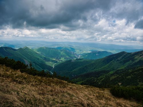 Free A scenic view of lush green mountains under an overcast sky in summer, offering a tranquil landscape. Stock Photo