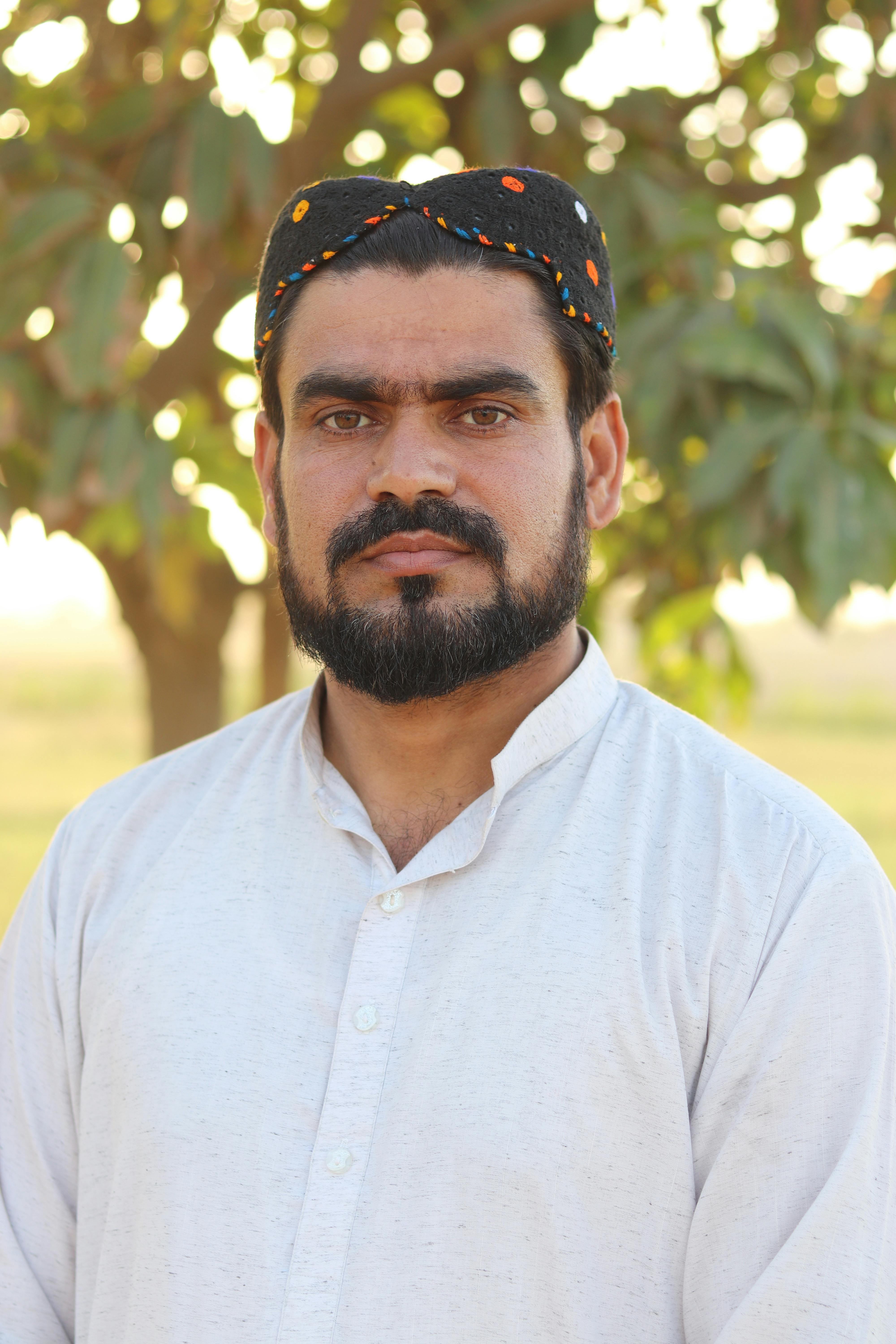 Close-up portrait of a bearded man wearing a traditional cap outdoors.