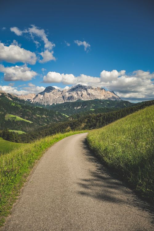 Free Breathtaking view of a mountain trail under a vibrant blue sky, surrounded by lush green hills. Stock Photo