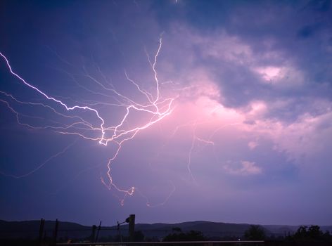 Captivating lightning bolts illuminate the night sky over a serene landscape.