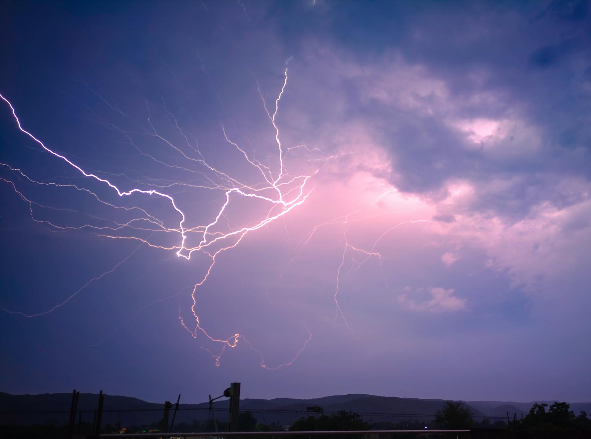 Captivating lightning bolts illuminate the night sky over a serene landscape.