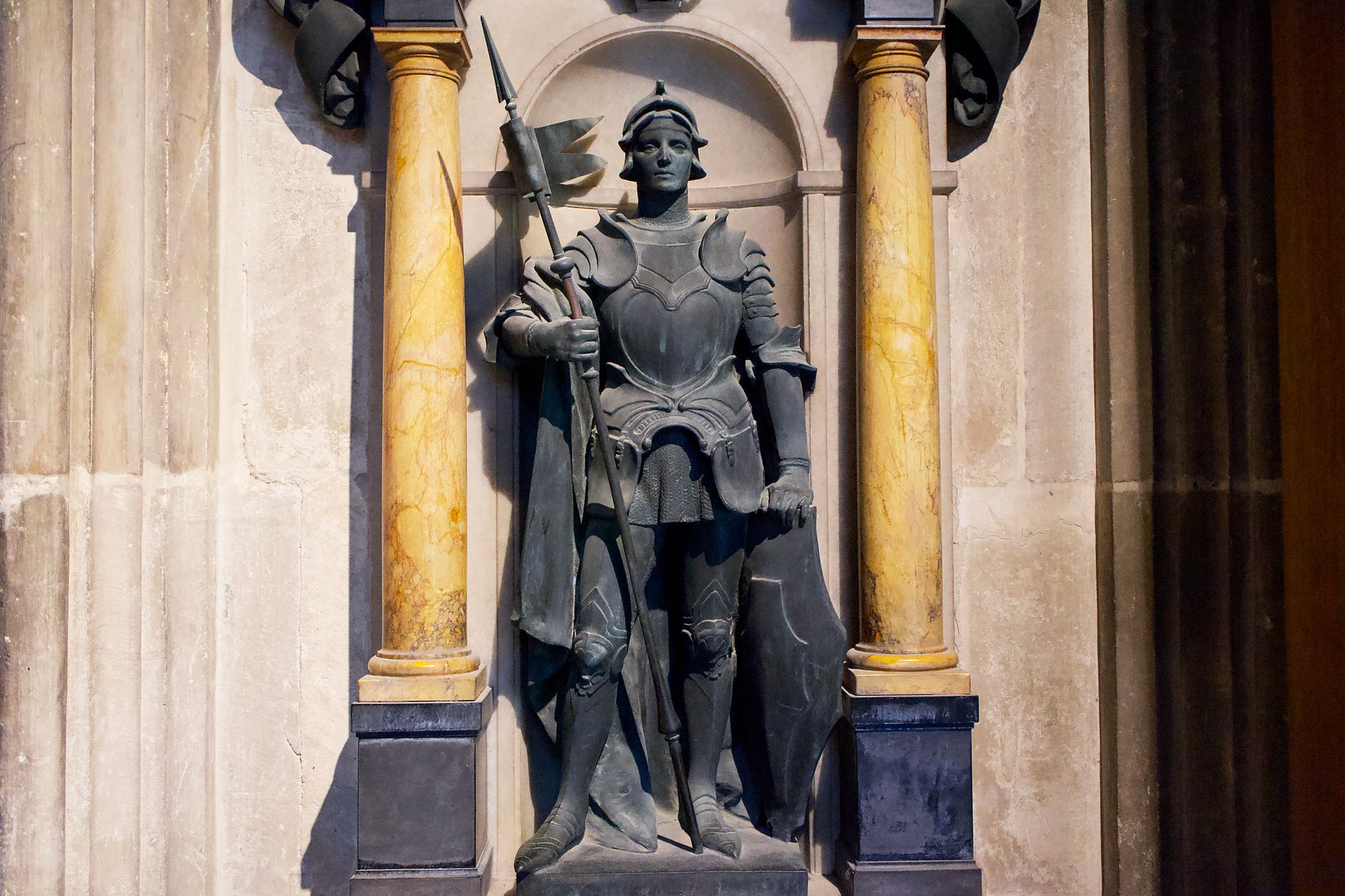 Detailed statue of a medieval knight in an English cathedral alcove.