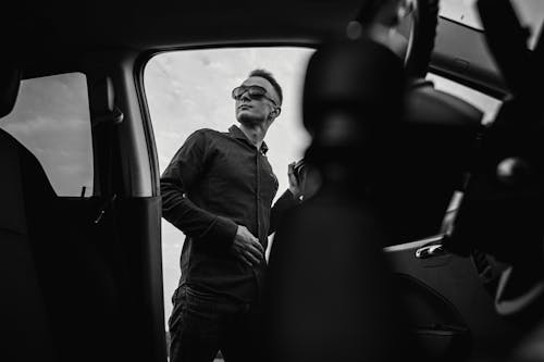 Grayscale Photograph of a Man Getting Out of a Car
