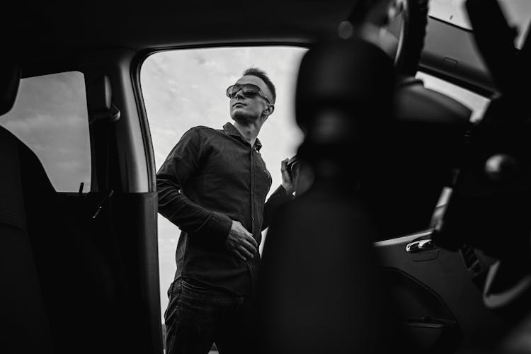 Grayscale Photograph Of A Man Getting Out Of A Car