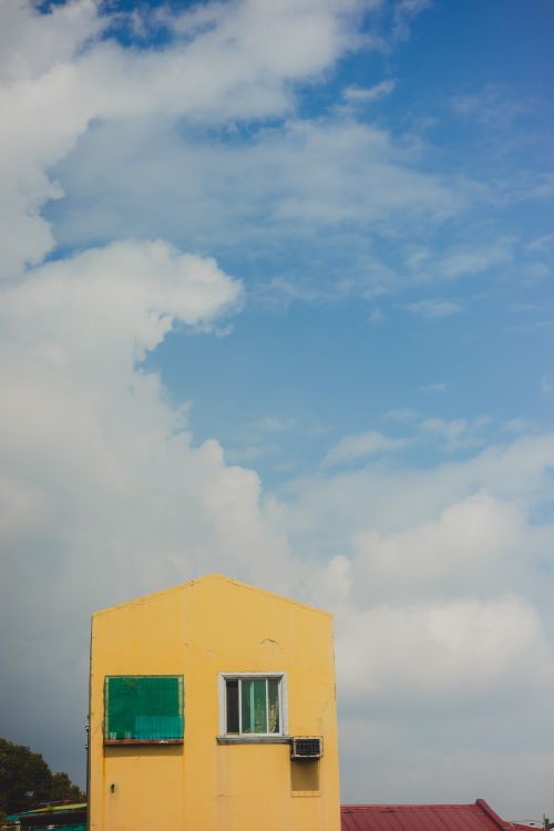 Free Vibrant yellow building under a clear blue sky, capturing contrast and simplicity. Stock Photo