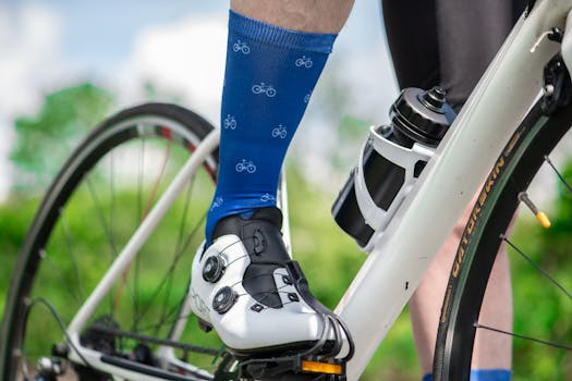 Close-up of a cyclist's leg with blue bike socks and cleats on a bicycle pedal outdoors.