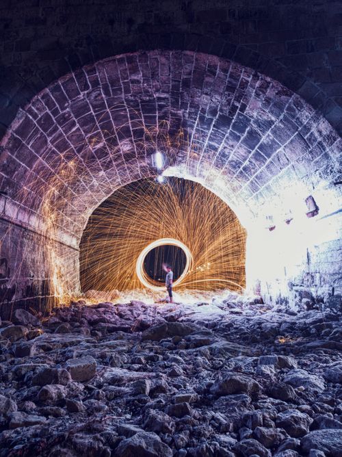 Free Long exposure of sparks and dramatic light in a rocky tunnel at night. Stock Photo