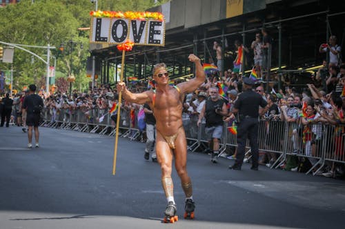 Man on Roller Skates Holding a Sign with the Word "Love" during a Pride Parade