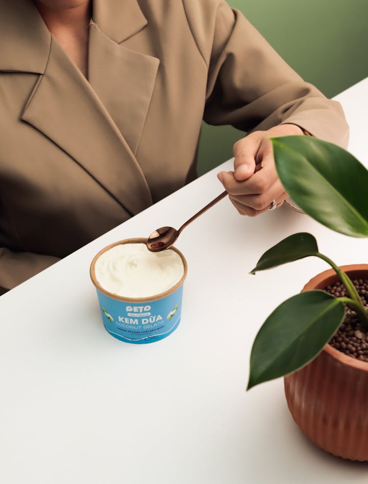 Person Eating Coconut Ice Cream With Spoon