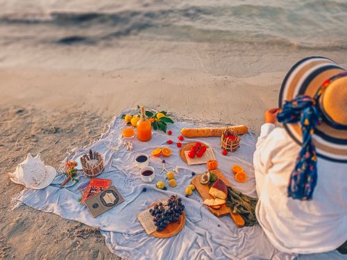 Free Cozy beach picnic setup with fruits and bread, perfect for a relaxing day by the sea. Stock Photo