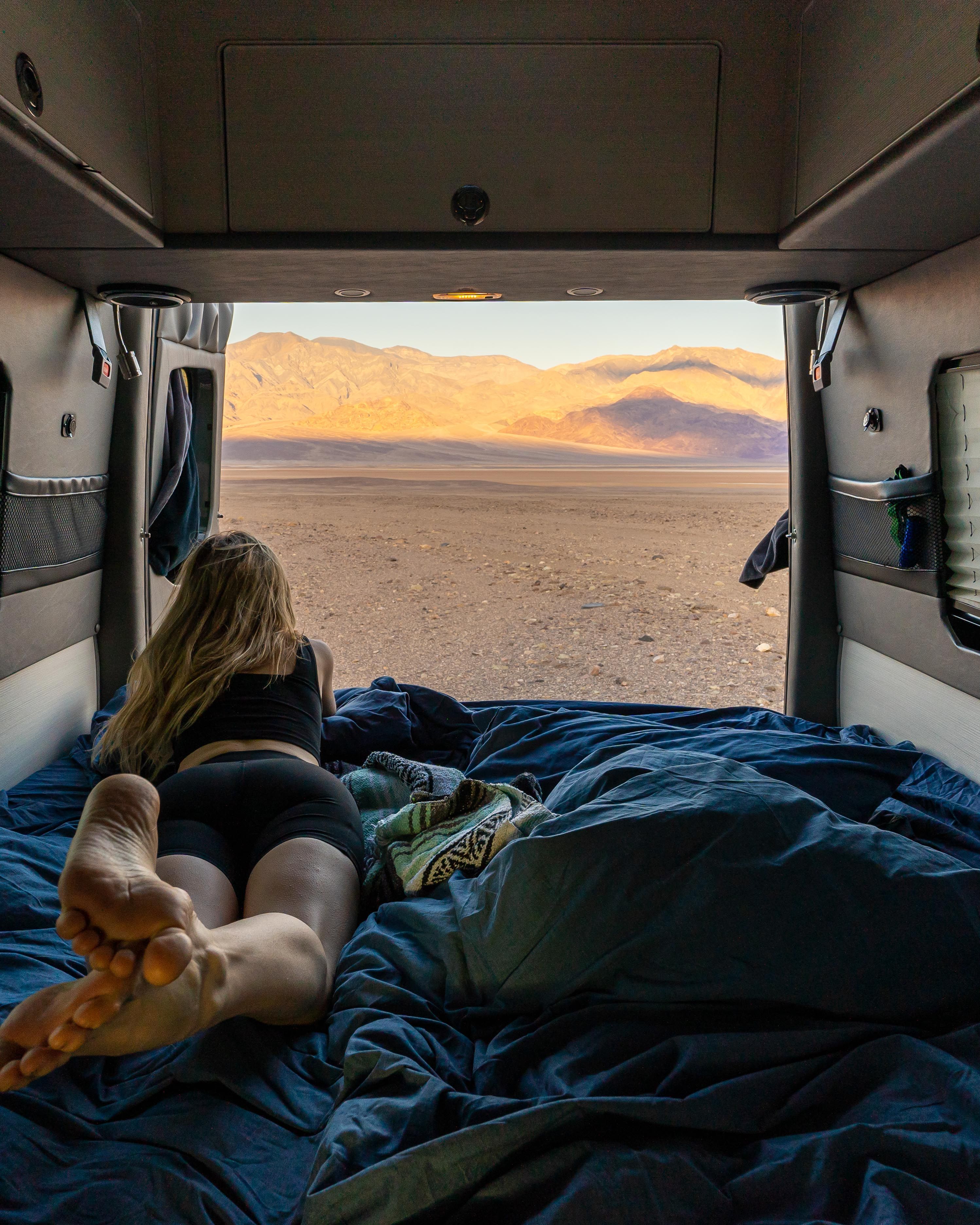 A woman enjoys the view from a camper van in the California desert, embracing van life.