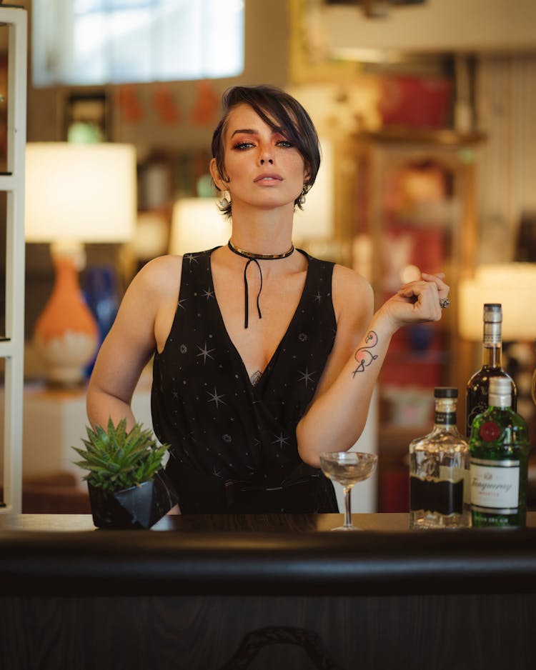 Woman Wearing Black Sleeveless Dress Standing Near Bar Counter