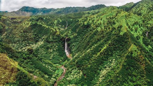Free Explore the lush green valley with a magnificent waterfall amidst verdant mountains. Stock Photo