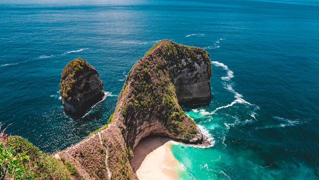 Stunning aerial shot of Kelingking Beach on Nusa Penida, Bali, with clear blue sea and dramatic cliffs.