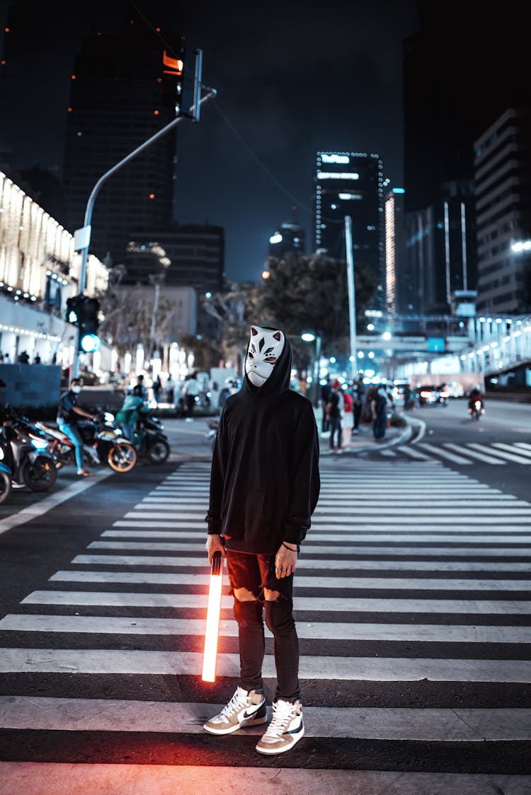 Masked Person With Light Saber On City Street At Night