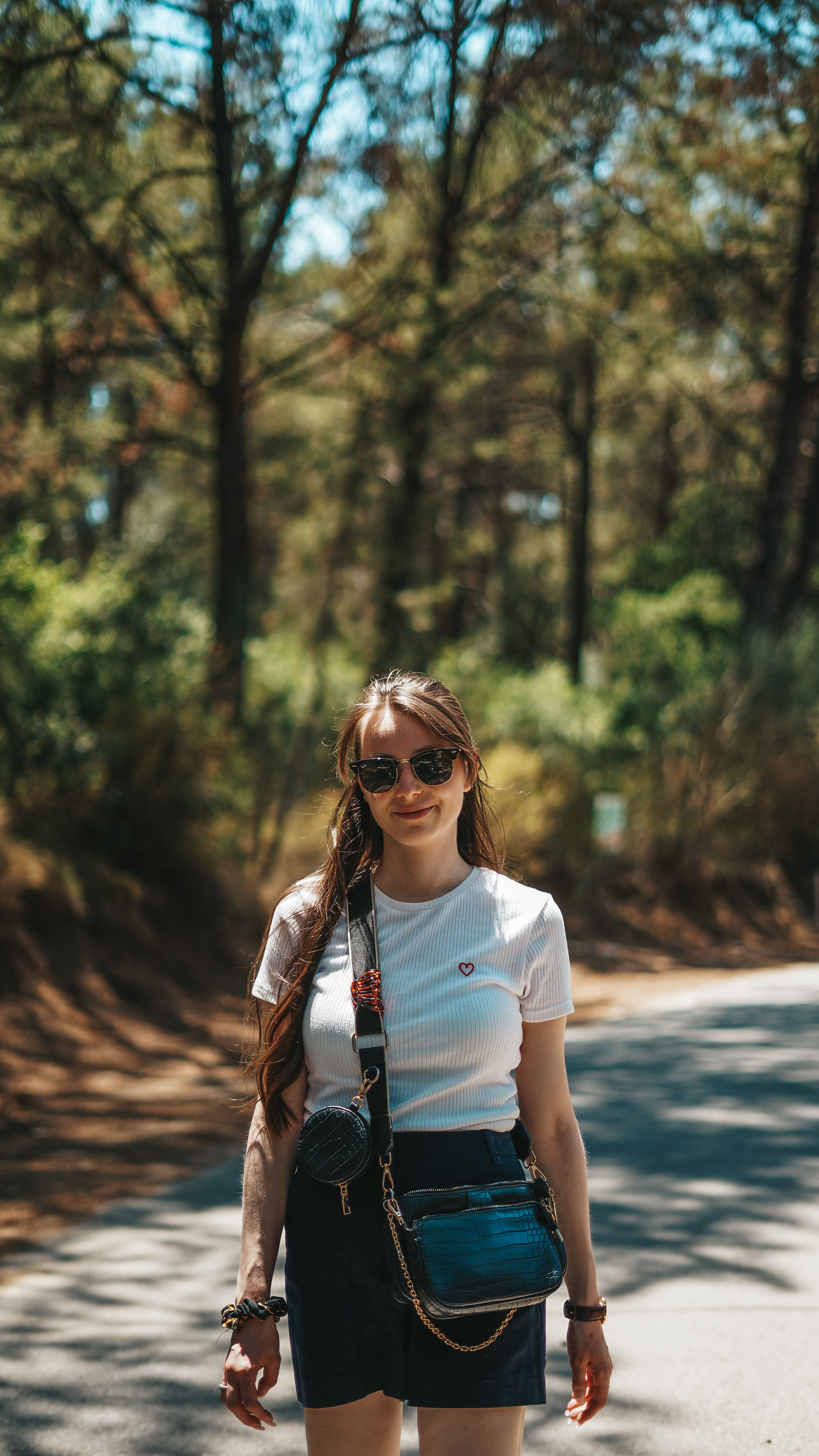 A young woman enjoying a hike on a sunlit forest path in Özdere, İzmir, Türkiye.