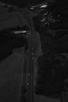 A high contrast aerial shot of a rural highway with flowing traffic captured at night.