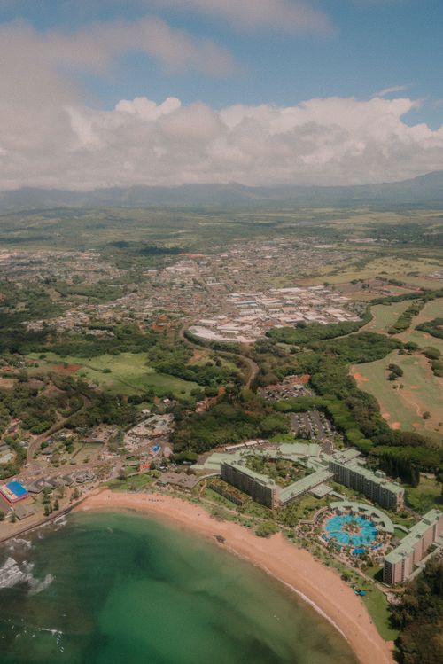 Free Stunning aerial view showcasing a tropical beachfront resort against a lush, vibrant cityscape with rolling hills. Stock Photo