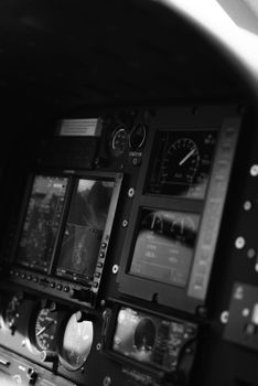 A detailed black and white shot of an aircraft's instrument gauges in a cockpit, showing avionics.