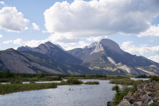 Stunning landscape of the Canadian Rockies with a river under a partly cloudy sky.